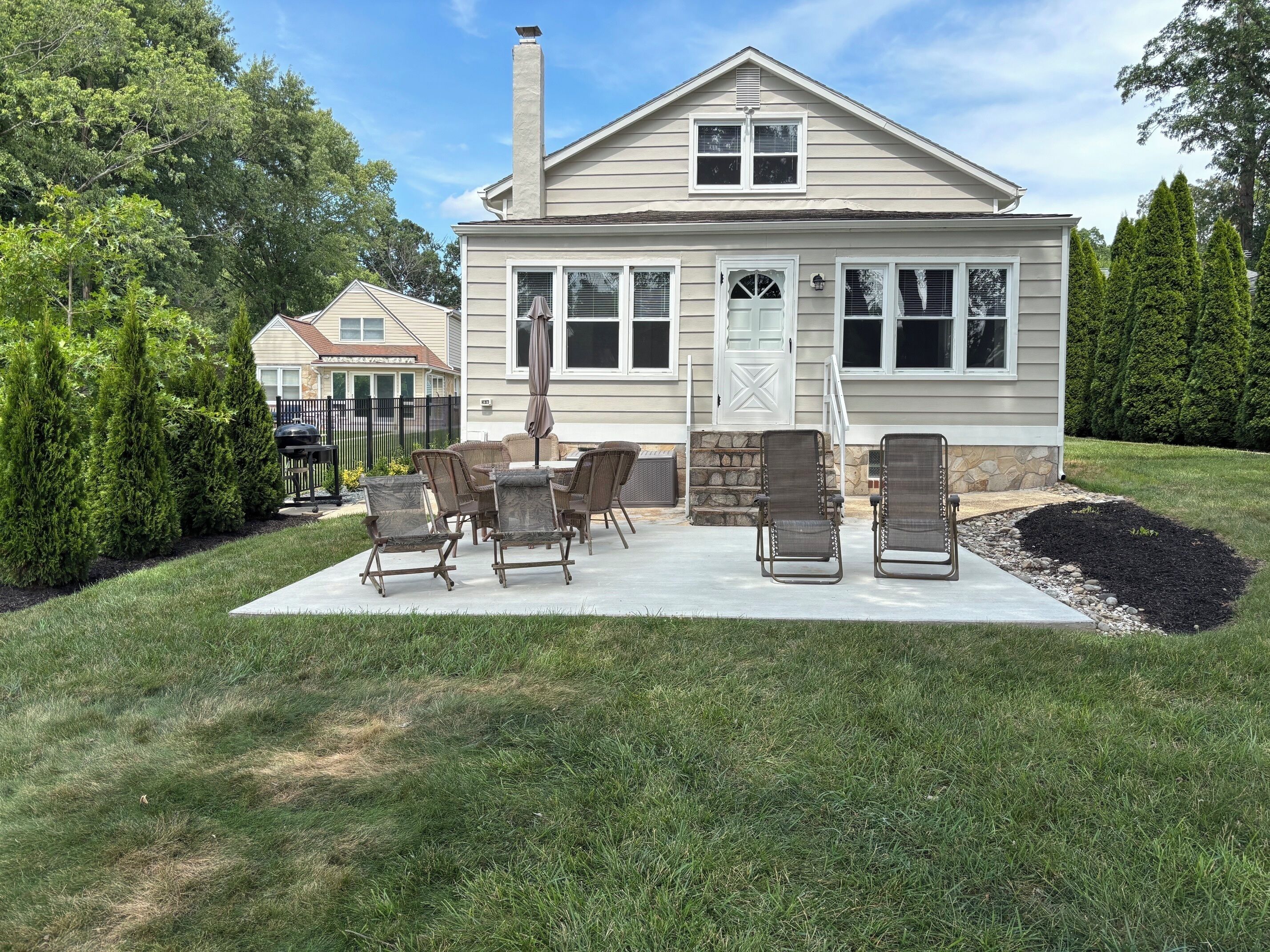 A house with a patio, outdoor seating, and a stone staircase leading to the entrance.