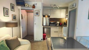 A compact living space with a kitchenette, a dining area, and a sofa.