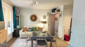A compact living space with a sofa, a glass-top dining table, and a TV on a cabinet.