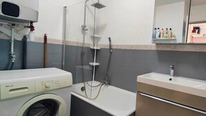 A bathroom with a washing machine, a bathtub, and a sink.