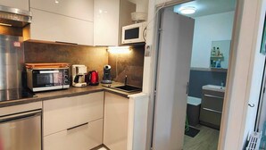 A compact kitchen with a microwave, coffee maker, and a stove.