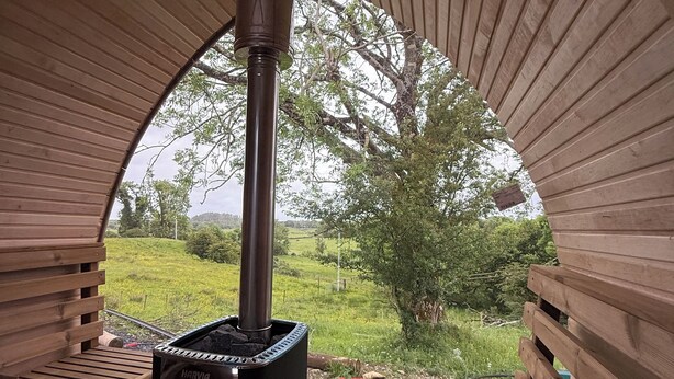 A wood-burning stove in a semi-circular wooden structure with benches. - Connemara Mountain Lakes Retreat. Hot Tub + Sauna. Sleeps 8. Pet friendly.  (Connemara)