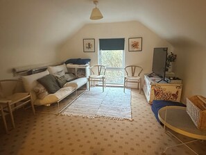 A cozy, well-lit room with a sofa, two chairs, a small table, and a window with blinds.