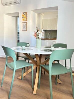 Un coin repas avec une table ronde, quatre chaises et un vase de fleurs.