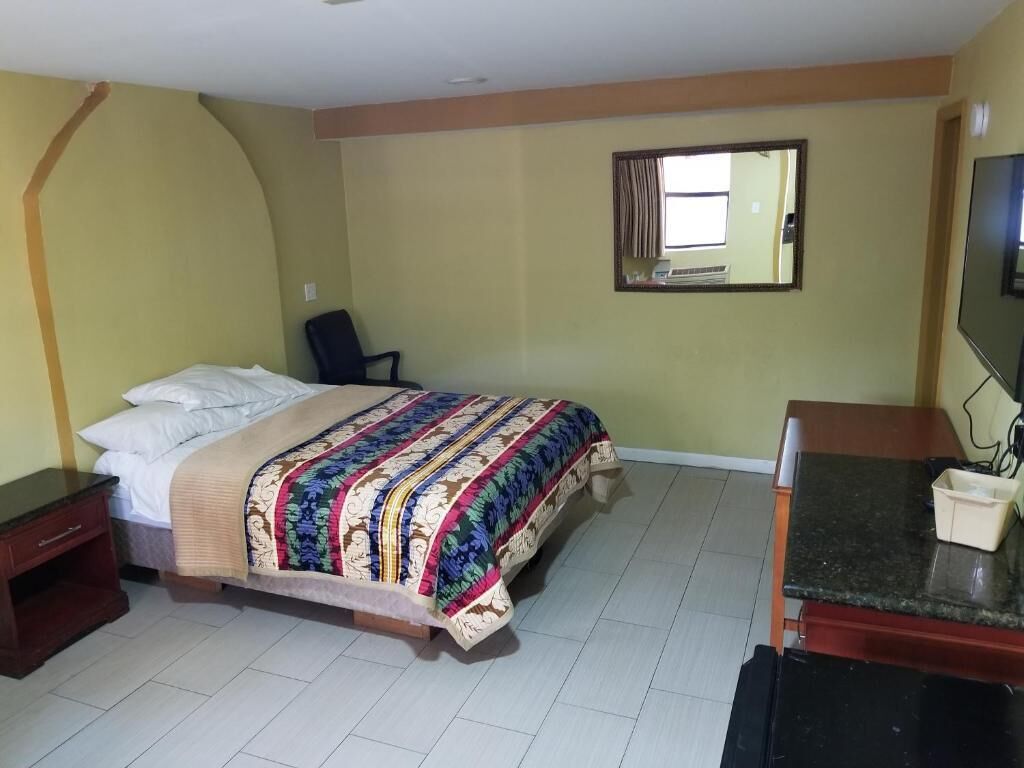 A hotel room with a bed, a desk, a chair, a television, and a window.