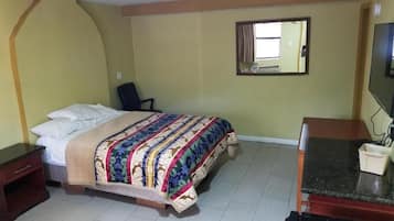 A hotel room with a bed, a desk, a chair, a television, and a window.