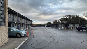 A parking lot with multiple cars and a building with a row of rooms. - Budget Motel (Orlando)