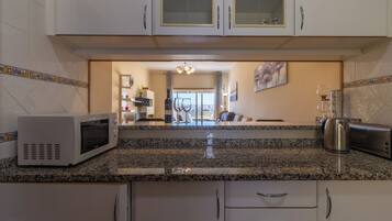 Apartamento, sacada, vista para a praia | Cozinha privada | Frigobar, micro-ondas, fogão, cooktop