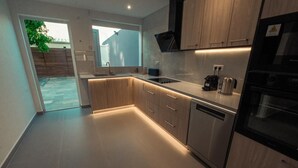 A modern kitchen with wooden cabinets, a built-in oven, and a dishwasher. - Villa d'Exception avec Piscine - 3 Min de la Plage 4 chambres climatisées (Sainte-Anne)