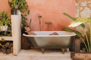 A bathtub in a rustic setting with plants and a stone wall. - Historic Colonial Gem with Private Pool in Santo Domingo (Santo Domingo)