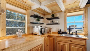 Eine moderne Küche mit Holzausstattung, einer eingebauten Mikrowelle und einem großen Fenster mit Blick ins Freie.
