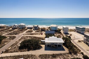 A coastal area with beach houses, a road, and a clear view of the ocean.