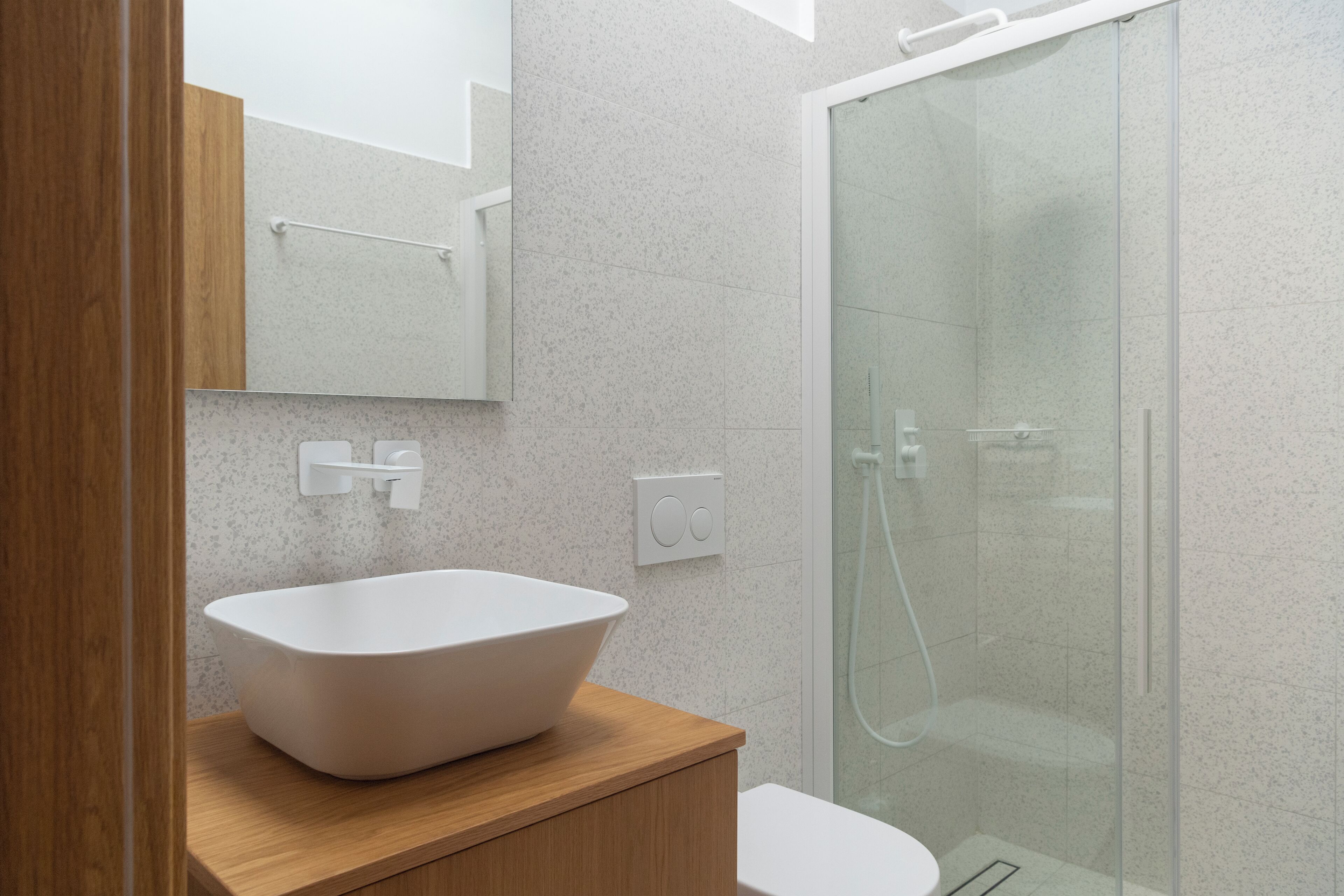 A modern bathroom with a freestanding bathtub, a glass shower enclosure, and a wooden vanity.