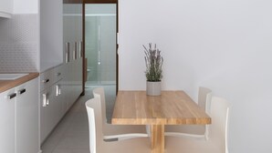 Una cucina moderna con mobili bianchi, un tavolo di legno e due sedie bianche.