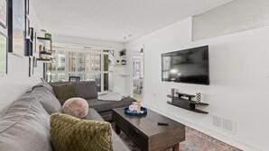 Ein modernes Wohnzimmer mit einem grauen Sofa, einem Couchtisch und einem flachbildfernseher an der Wand.