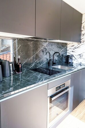 A modern kitchen with a black marble countertop, stainless steel sink, and built-in oven.