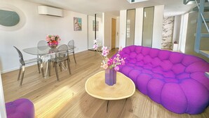 A modern living space with a dining area, a purple sofa, and a staircase.