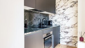 A modern kitchen with a marble backsplash, stainless steel appliances, and dark cabinetry.
