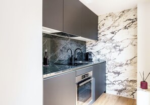 A modern kitchen with a marble backsplash, stainless steel appliances, and dark cabinetry.