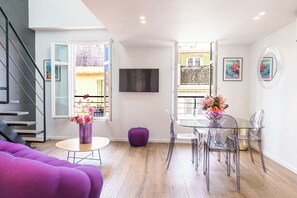 A modern living space with a dining area, a staircase, and a balcony with a view.