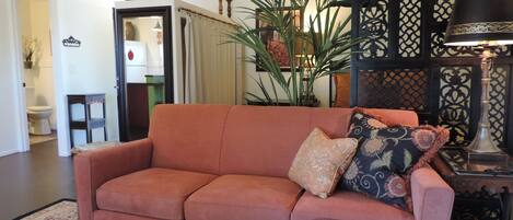 En stue med sofa, et tæppe med et mønster, en potteplante og en dekorativ lampe.