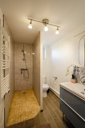 Un baño con ducha, inodoro y tocador.