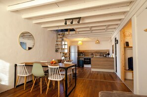 Una cocina moderna con piso de madera, un comedor con sillas y un horno empotrado.