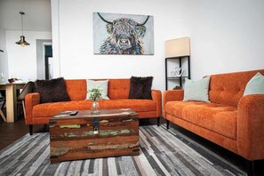 Una sala de estar moderna con un sofá, una mesa de centro y una obra de arte en la pared.