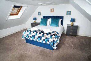 Un dormitorio con cama, dos mesitas de noche, una ventana y techo inclinado.