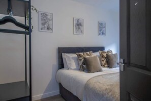 A bedroom with a bed, a wardrobe, and three framed artworks on the wall.