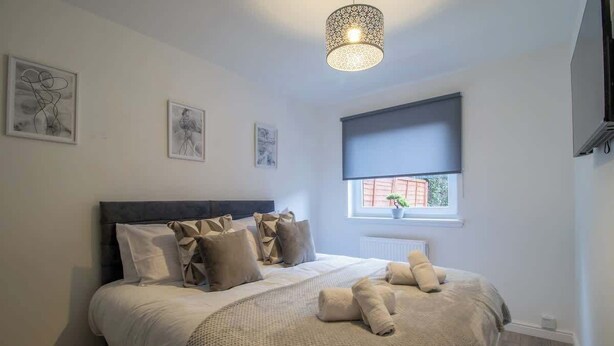 A bedroom with a bed, a window with a view, and a ceiling light fixture. - The Larky - Modern 2 Bed Cottage in Larkhall (Larkhall)