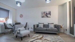 A modern living room with a grey sofa, a coffee table, and a patterned rug. - The Larky - Modern 2 Bed Cottage in Larkhall (Larkhall)