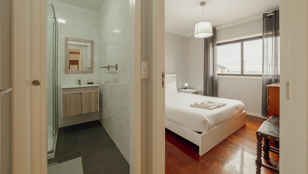 Une chambre d’hôtel moderne équipée d’une douche, d’une table de chevet, d’un lit et d’une fenêtre donnant sur un paysage agréable.
