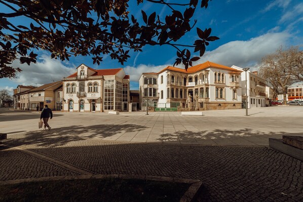 A spacious public square with historic buildings featuring arched windows and a tiled roof.