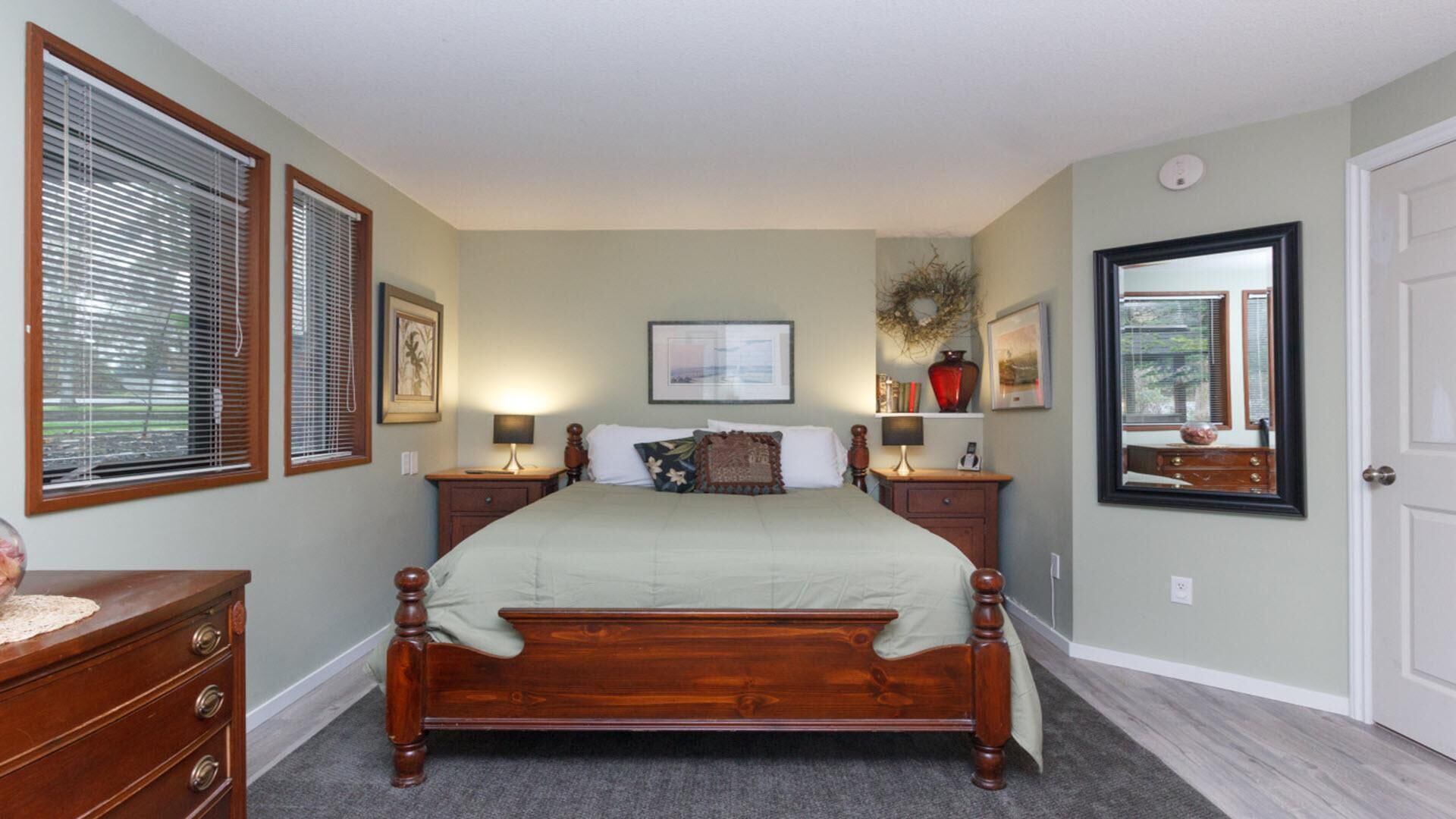 Une chambre à coucher avec un grand lit, deux tables de chevet, une commode et un miroir.