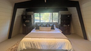 A bedroom with a large bed, two nightstands, and a window with a view of trees. - Cozy 3-Level cabin in Groveland with WiFi, stunning views, deck and hot tub (Groveland)
