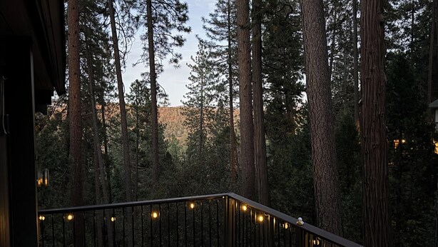 A hot tub on a wooden deck with a railing, surrounded by tall pine trees. - Cozy 3-Level cabin in Groveland with WiFi, stunning views, deck and hot tub (Groveland)