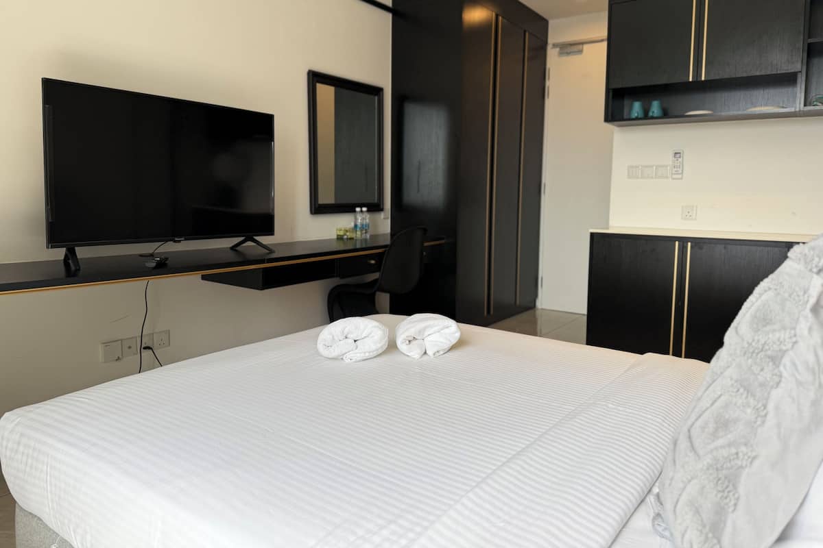 Ein Hotelzimmer mit Bett, Fernseher, Schreibtisch und Kleiderschrank.