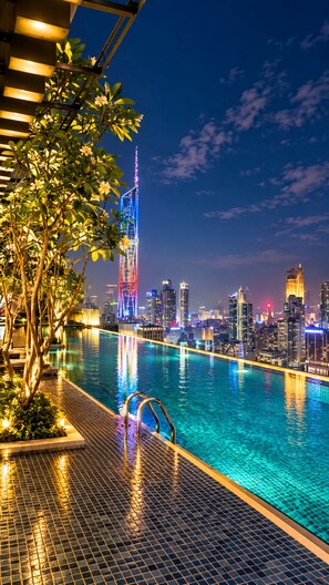 A nighttime poolside view with a city skyline in the background.