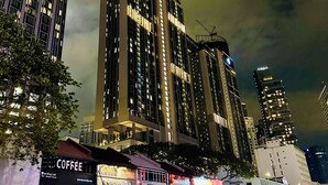 Paisaje urbano nocturno con edificios altos, incluyendo un hotel destacado con un letrero iluminado.