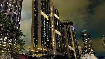 A nighttime cityscape with tall buildings, including a prominent hotel with a lit sign.