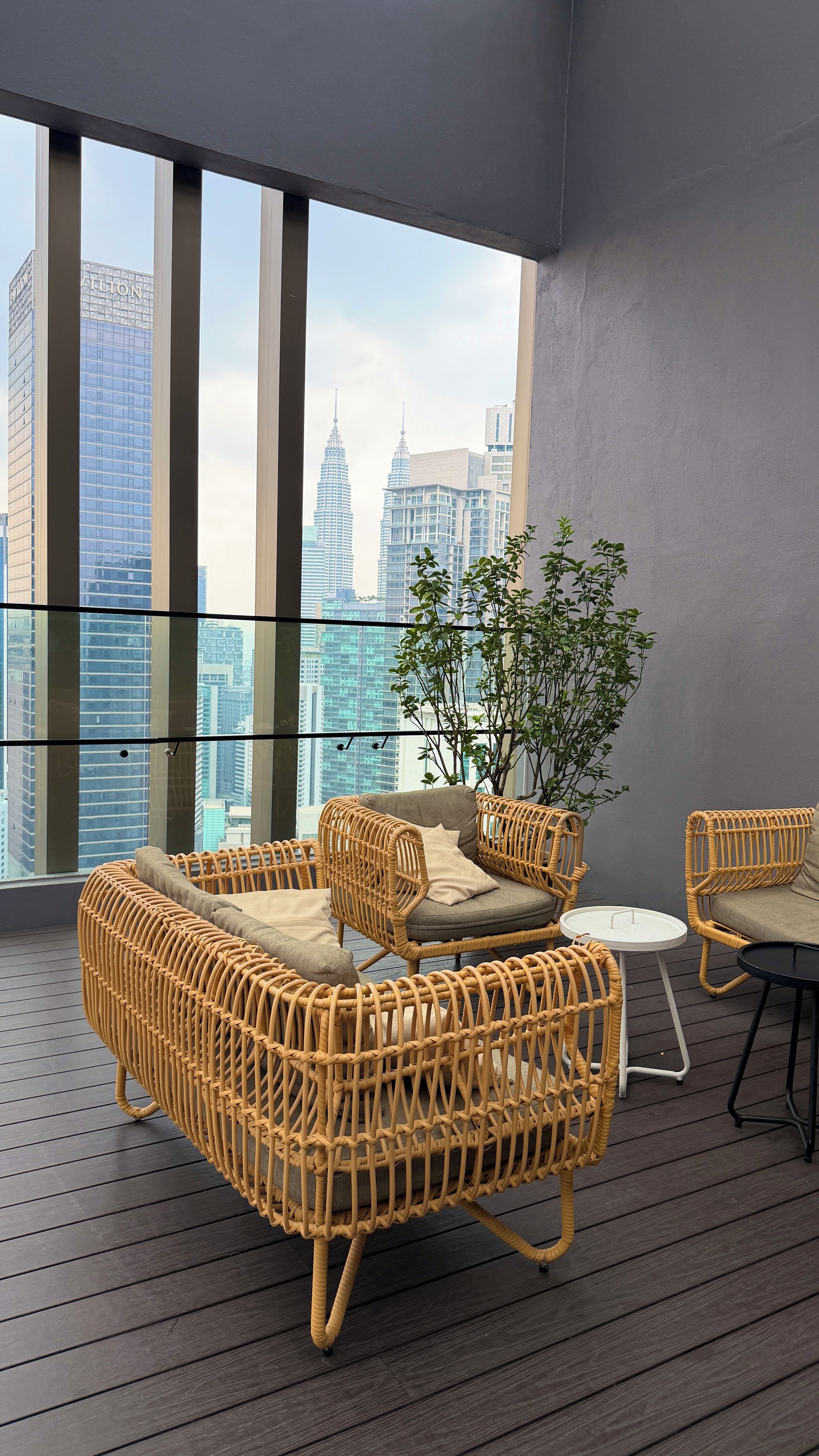 A balcony with wicker furniture, a glass table, and a potted plant.
