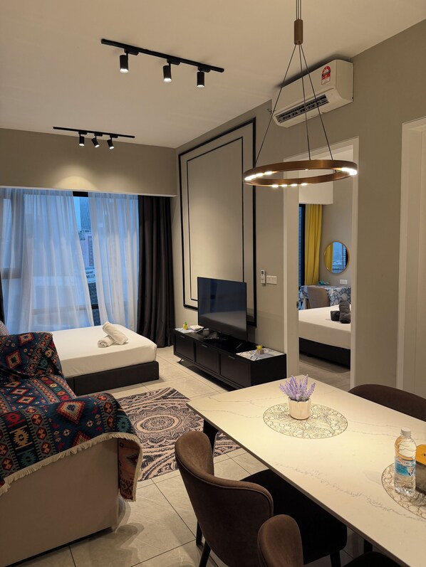 Una habitación de hotel moderna con cama, televisión, mesa de comedor y sofá.