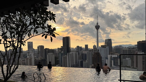 Una piscina infinita con vistas al horizonte urbano, incluyendo una torre destacada.