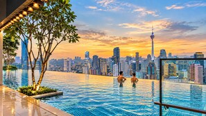 Una piscina infinita en la azotea con vistas al horizonte de la ciudad, incluyendo una torre destacada.