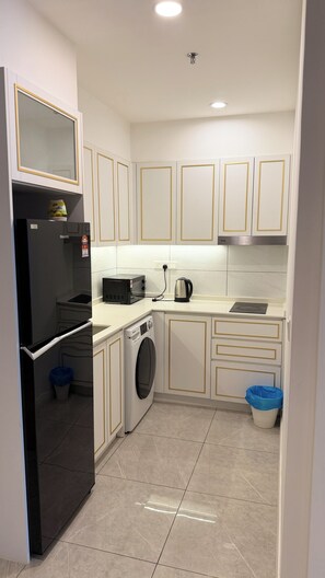 Cocina compacta con refrigerador, microondas, hervidor y lavadora.