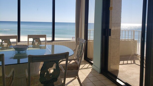 A balcony with a table and chairs overlooking a beach.