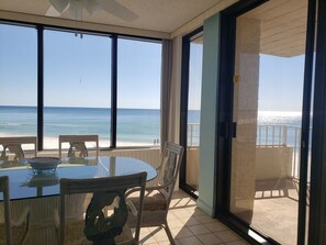 Un balcon avec une table et des chaises donnant sur une plage.