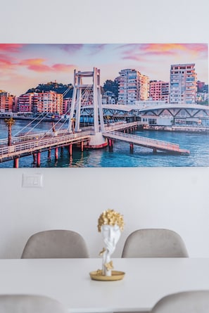 A cityscape with a bridge over water, modern buildings, and a table with a vase.