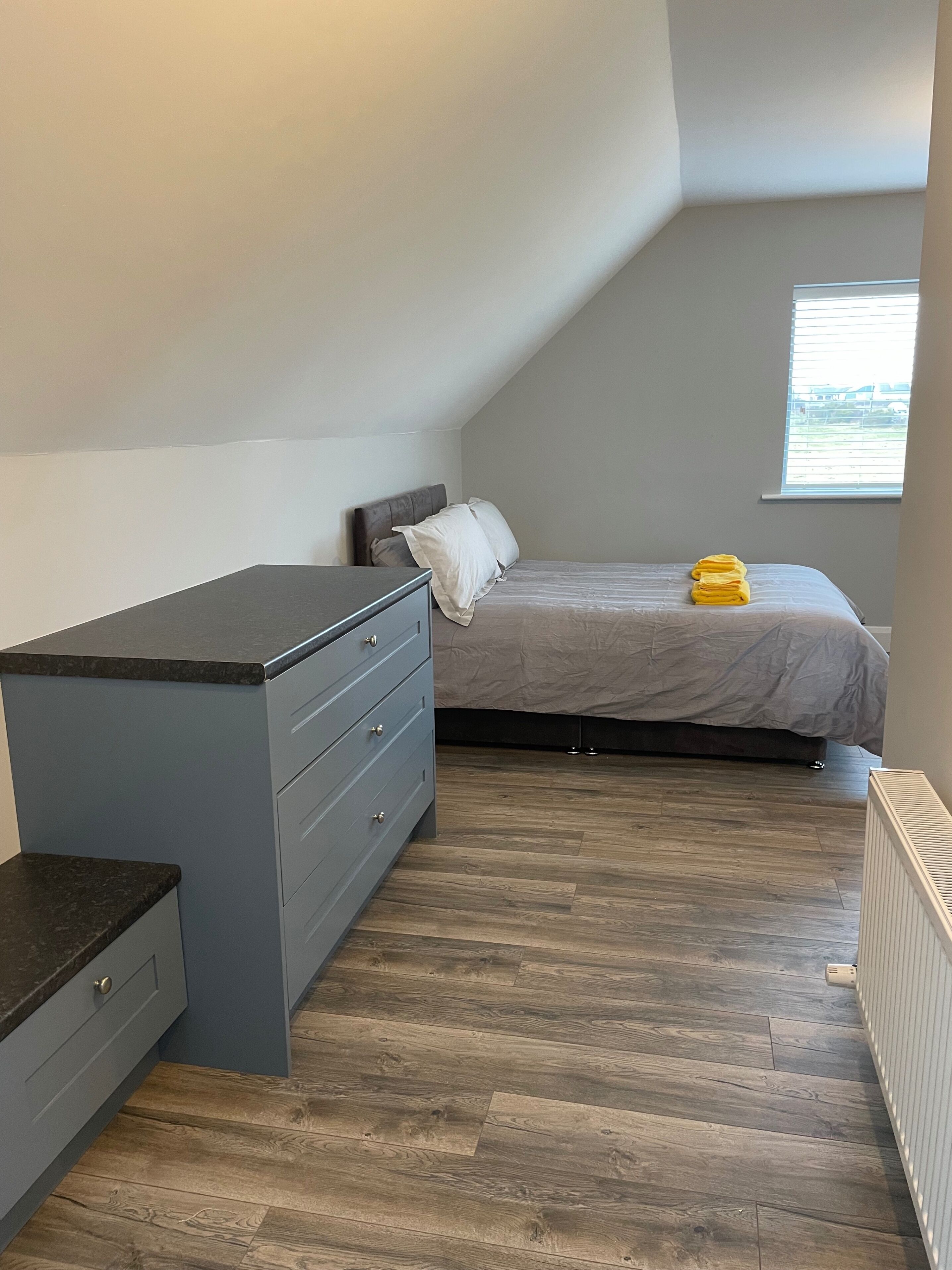 Un dormitorio con cama, cómoda y ventana.